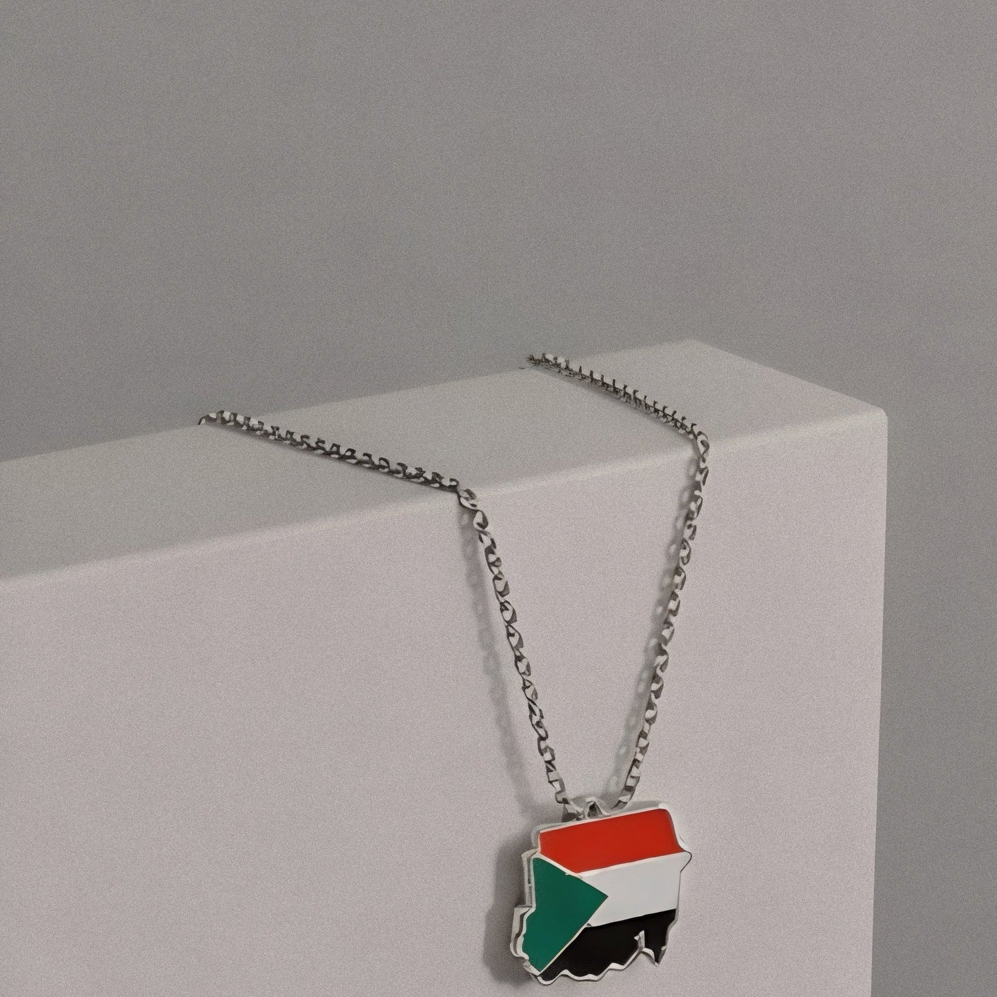 Necklace with a flag pendant on a gray background, featuring Balance Studios branding.